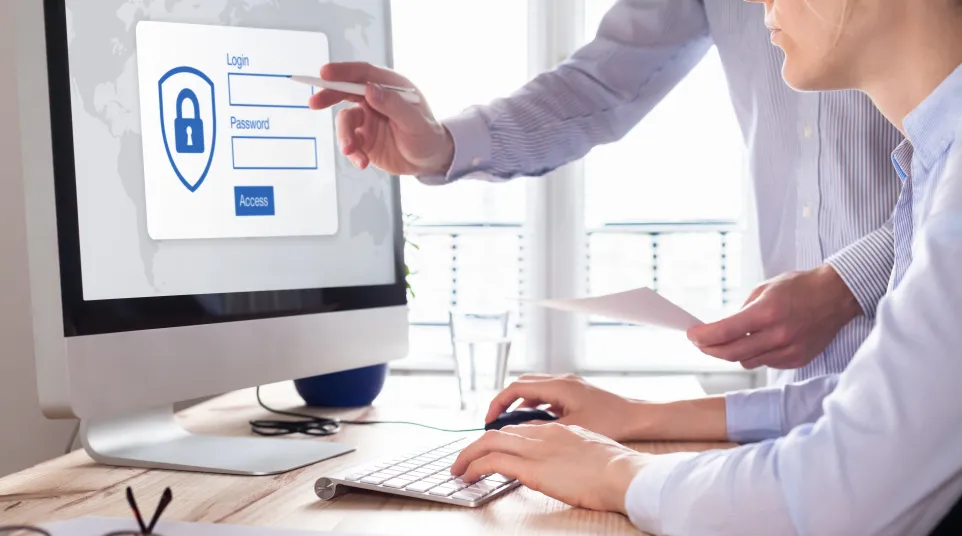 Person logging into a computer, focusing on password entry and security, with a second person guiding.